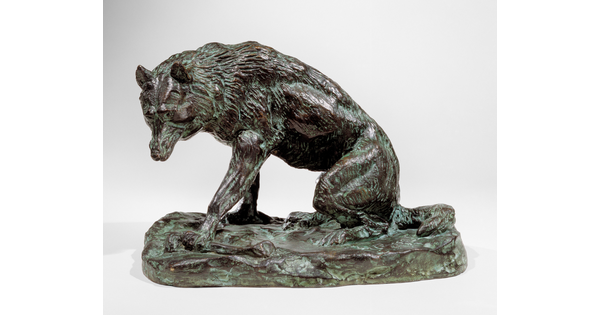 A bronze sculpture of a wolf crouching on its haunches.