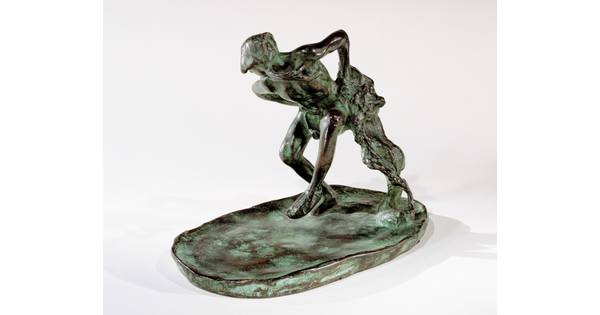 A bronze sculpture of an Indigenous man dancing with a wolfskin in his hand.