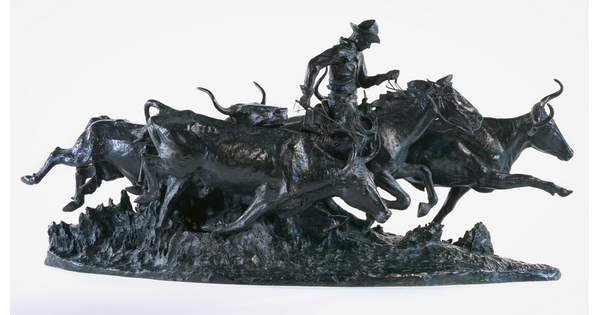 A bronze sculpture of a cowboy on a running horse surrounded by stampeding cattle.