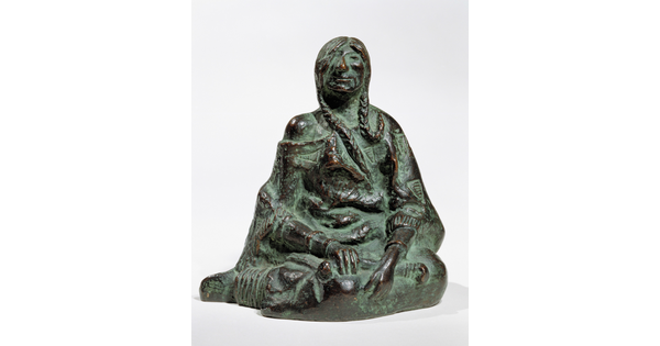 A bronze sculpture of a seated Native American person wrapped in a robe.