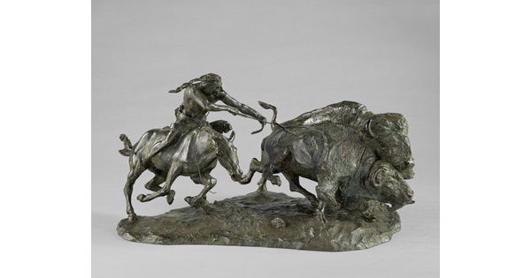A sculpture of a Native American on horseback using a bow and arrow to hunt two bison.