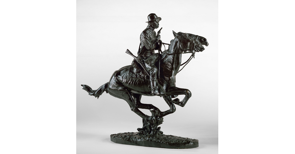 A bronze sculpture of a cowboy riding a galloping horse and holding a pistol close to his chest.
