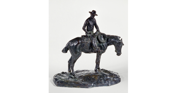 A bronze sculpture of a man wearing a cowboy hat seated on a standing horse.
