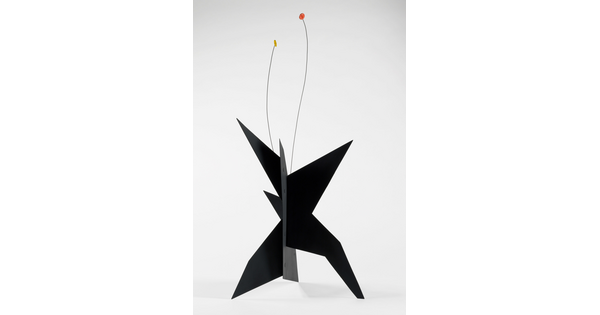 A black, metal, star-like shaped sculpture with two wires rising from the top, one capped with a yellow circle and the other with an orange circle.