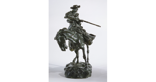 A bronze sculpture of a man on horseback pointing a long rifle.