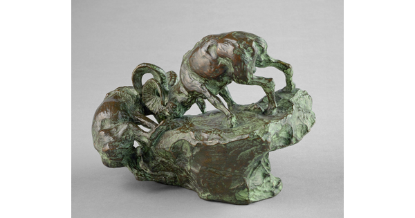 A bronze sculpture of two mountain sheep fighting on the edge of a rock.