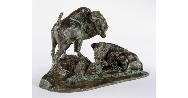 A bronze sculpture of two bison, one lying down and the other standing.