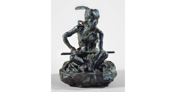 A bronze sculpture of an Indigenous man seated on the ground with a rifle resting across his lap.