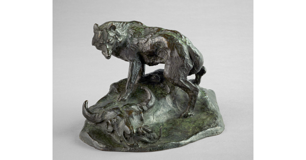A bronze sculpture of a wolf standing over a bison skull with a rattlesnake hiding inside.