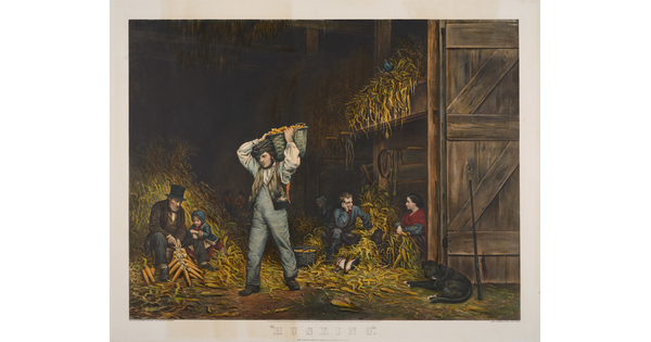 A color print of a group of White people of various ages husking corn in a barn; discarded husks piled in heaps around them.