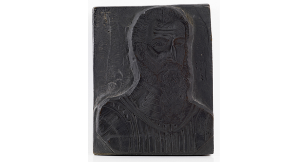 A metal printing block with a portrait of the head and shoulders of a bearded man wearing armor.