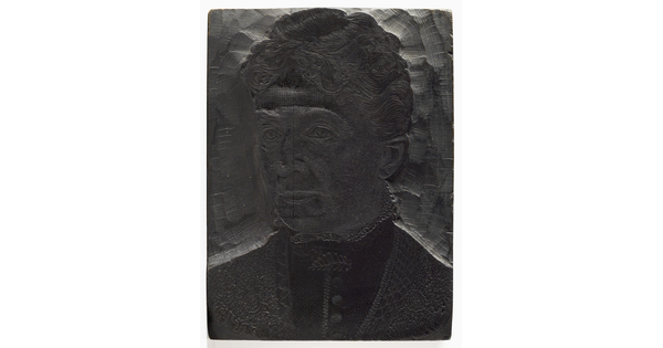 A metal printing block with a portrait of the head and shoulders of a middle-aged woman in Victorian dress with a fern-leaf brooch at her throat.
