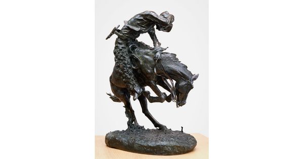 A bronze sculpture of a cowboy riding a bucking horse around a rattlesnake.