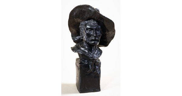 A bronze bust of a mustached man wearing a cowboy hat and a kerchief around his neck.