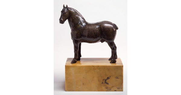 A bronze sculpture of a stallion with a bobbed tail standing on a stone base.