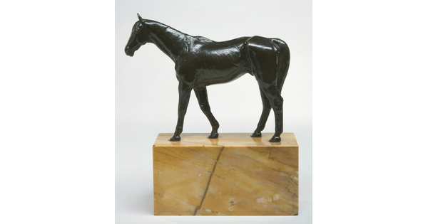 A bronze sculpture of a muscular horse with a long tail on a base of yellow marble.
