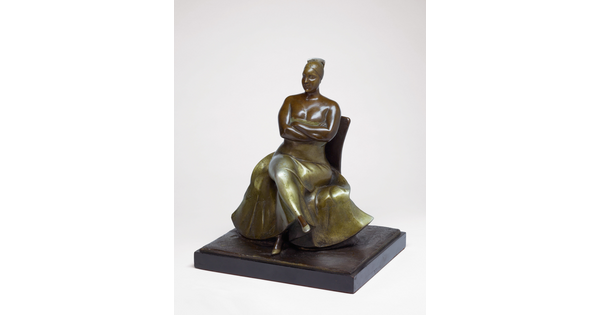 A bronze sculpture of a woman wearing an evening gown sitting with her legs and arms crossed.