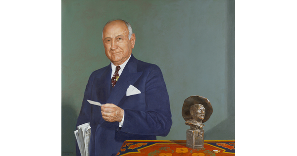 An oil painting of an older White man holding newspapers under his arm and standing next to a table on which sits a Remington sculpture.