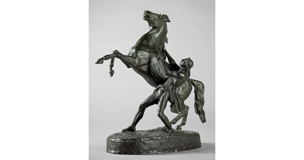 A bronze sculpture of a Native American man holding back a rearing horse.