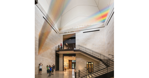 A large installation of multicolored sewing thread that stretches from one wall to the ceiling in the Carter's Atrium and looks like a rainbow.