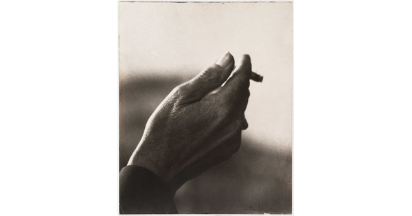 A sepia-toned close-up photograph of a right hand holding an almost-finished cigarette.