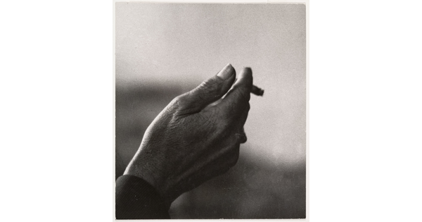 A black-and-white close-up photograph of a right hand holding an almost-finished cigarette.