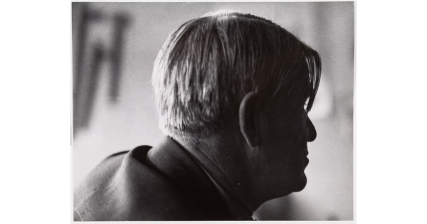 A black-and-white photograph of a man's head in profile with longer pieces of hair hanging over his right eye.