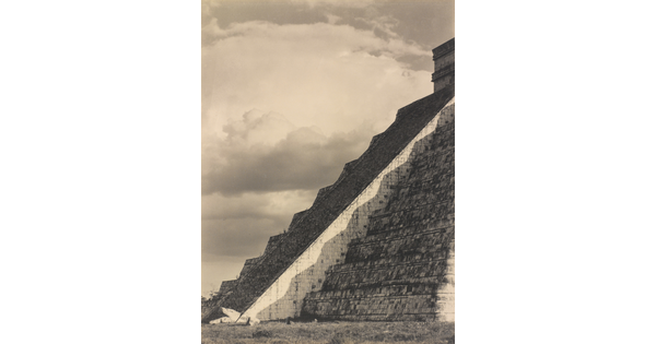 A black-and-white photograph of the diagonal corner edge of a Mayan step-pyramid.