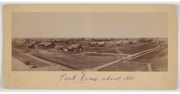 A sepia-toned panoramic photograph of a town with roads and buildings.