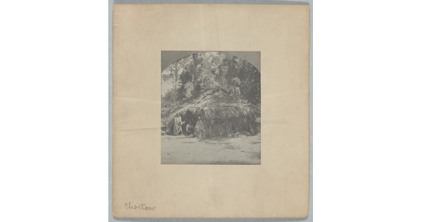 A black-and-white photograph of a wigwam with three figures in the doorway.