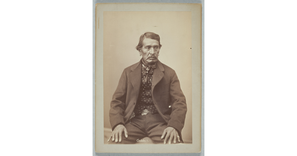 A sepia-toned portrait photograph of a man wearing an open jacket, patterned shirt, and a bowtie.
