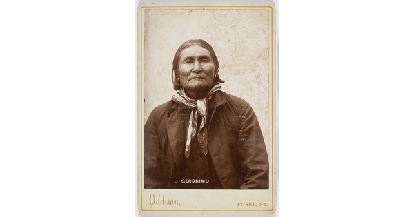 A black-and-white formal portrait photograph of an Indigenous man in a shirt, jacket, and neckerchief.
