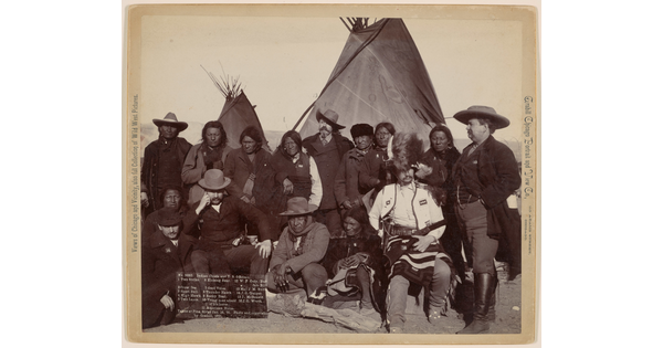 A black-and-white photograph of Indigenous men and U.S. officials in front of tipis.