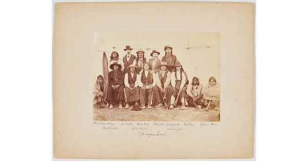 A sepia-toned photograph of a group of Indigenous people, some standing and some sitting.