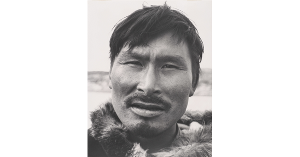 A black-and-white photograph of a close-up of an Indigenous man with a mustache wearing fur at his neck.