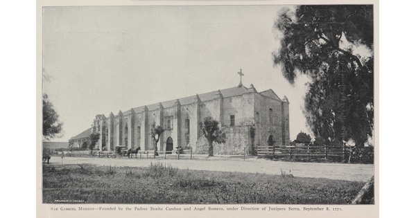 A black-and-white photograph of a mission church by a dirt road.