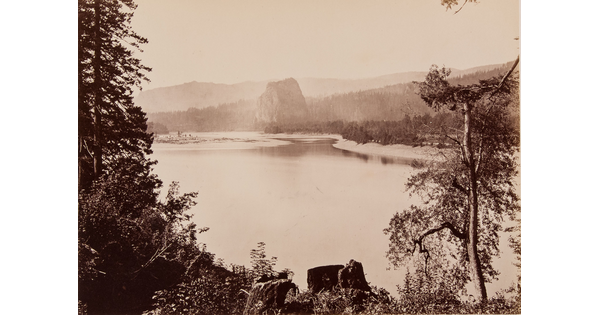 A sepia-toned photograph of a serene river surrounded by trees, rock formations, and mountains.