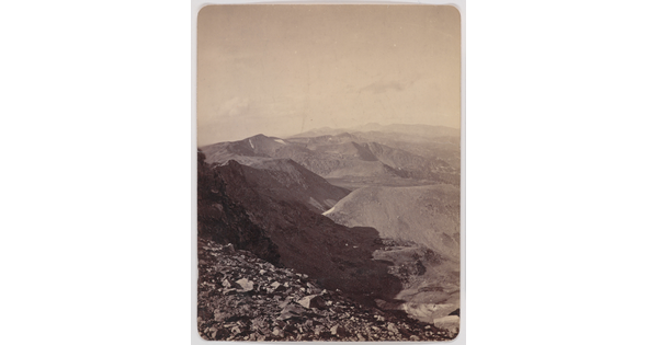 A black-and-white photograph of rocky mountains under a clear sky viewed from a high elevation.