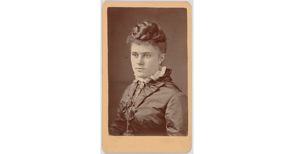 A black-and-white portrait photograph of a young White woman, hair braided and piled on top of her head, wearing a dark dress with a high lace collar.