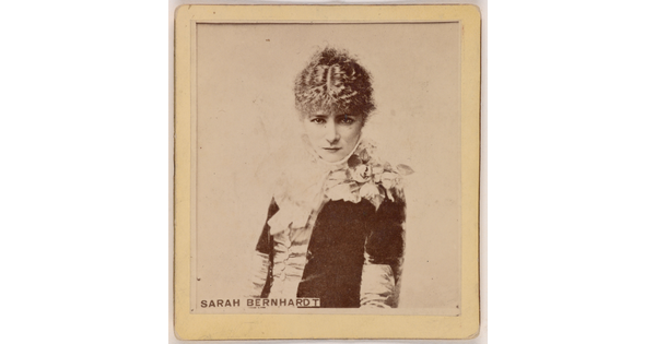 A sepia-toned portrait photograph of a young, White woman from the waist up, wearing formal, early 20th century clothing.