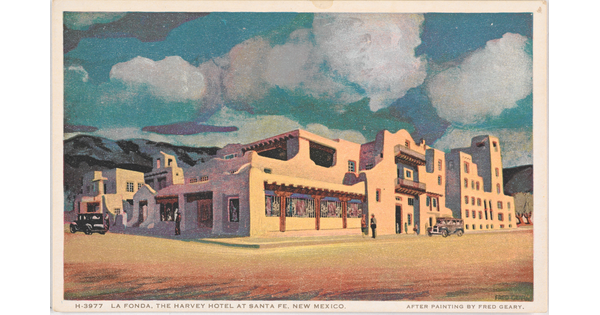 A color postcard of an adobe building with mountains and fluffy white clouds in the background.