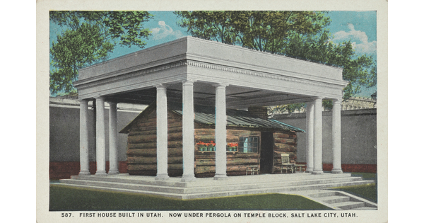 A color postcard of a log cabin covered by a columned structure.