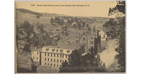 A sepia-toned photograph of large stone buildings in a valley with "Braun Bath House and Court House, Hot Springs, S.D." printed across the top.