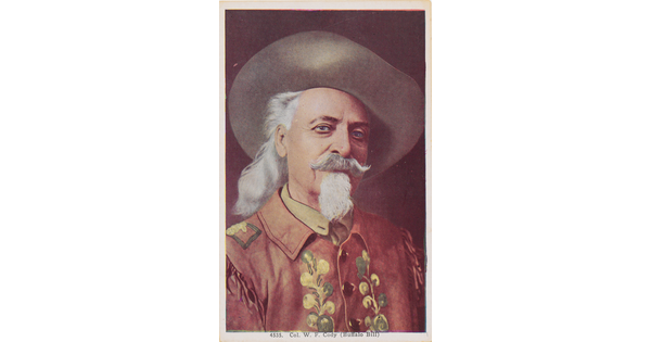 A color photograph postcard of a portrait of a White man wearing a cowboy hat, long gray hair, moustache and goatee, and a decorative jacket.