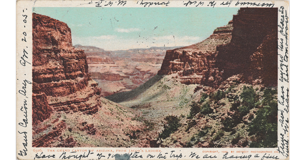 A color postcard of red rocks and a green valley of a canyon with black cursive handwriting around the border.
