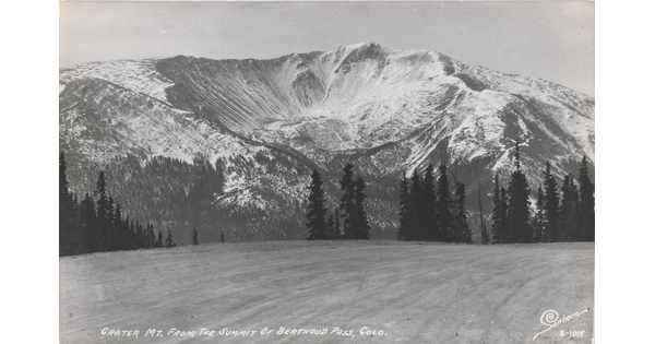 A black-and-white postcard of a crater in a large, snowy mountain.