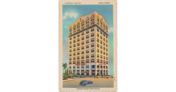 A color postcard of a multi-story hotel with many windows and cars parked in front.