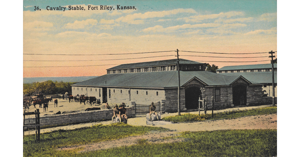A color postcard of a stone stable with horses in a paddock and riders around the perimeter.