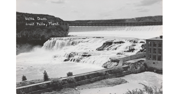 A black-and-white postcard of water flowing through a dam.