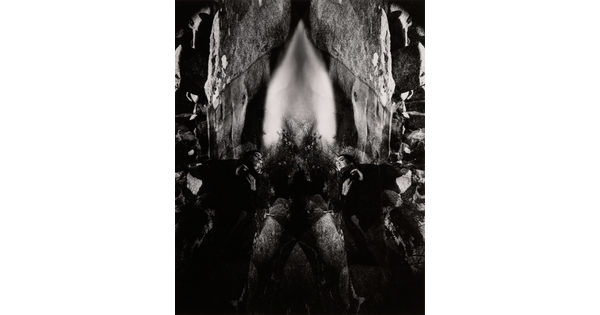 An abstract black-and-white photograph of rock formations, waterfalls, and other natural materials reflected to create a symmetrical design.